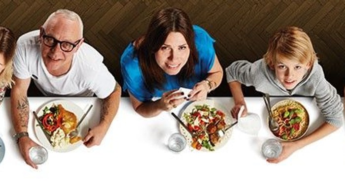 En gruppe af mennesker sidder sammen og spiser pizza.