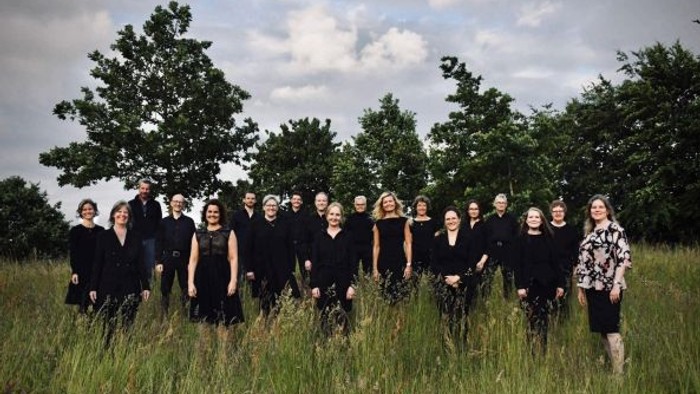 En gruppe af kvinder i svart klæder står sammen i en eng.