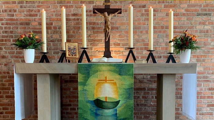 Bild zeigt eine Kirchenaltar mit Kreuz, Kerzen und Gemälde