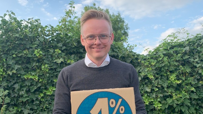 Mand holder en kasse med 1% skilt.