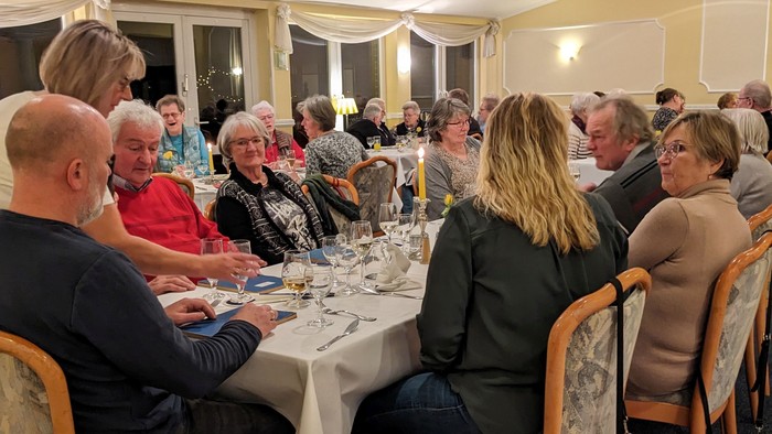 Eine Gruppe von Menschen sitzt an einem Tisch und isst gemeinsam in einem Raum.