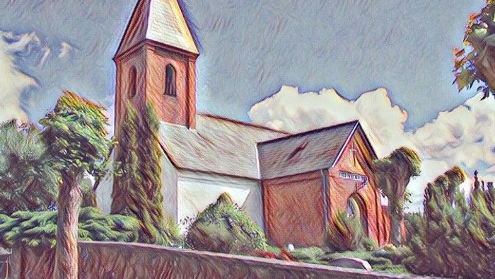 En maleriagtig kirke med tårn og træer i forgrunden