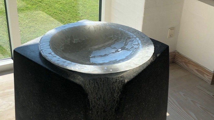 En moderne fontæne i et indendørs område med glaspanelet bagud