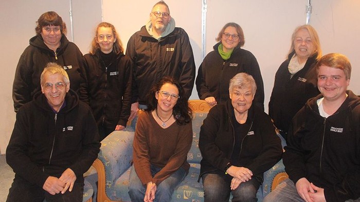 Eine Gruppe von Menschen posiert für ein Foto, einige sitzen auf einem Sofa, andere stehen hinter ihnen