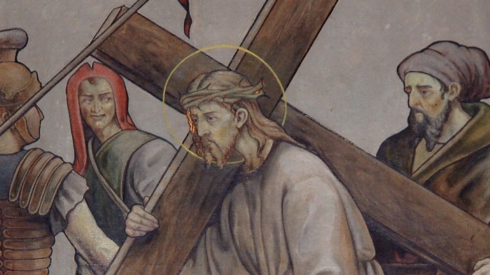 Jesus trägt das Kreuz, begleitet von zwei Männern und einer Frau.