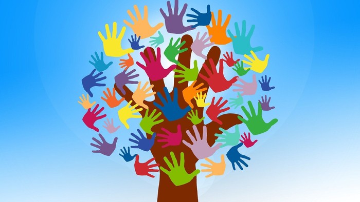 Viele bunte Hände bilden einen Baum vor blauem Himmel