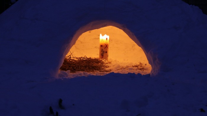 Eine kleine Schneehöhle mit warmer Beleuchtung im Schnee.