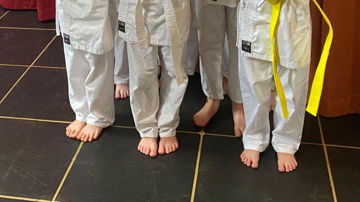 Vier Kinder in Karate-Uniformen stehen in einer Reihe