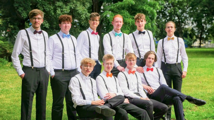 Eine Gruppe von Männern in Anzügen und Hosenträgern posiert im Park