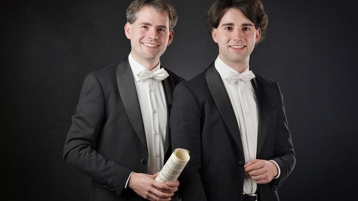 Zwei junge Männer im Anzug mit Rollen Toilettenpapier