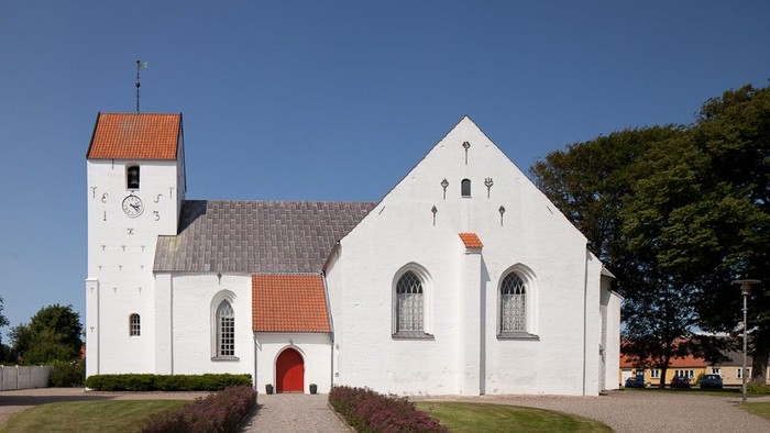 Hvid kirke med klokketårn og røde dør og tag.