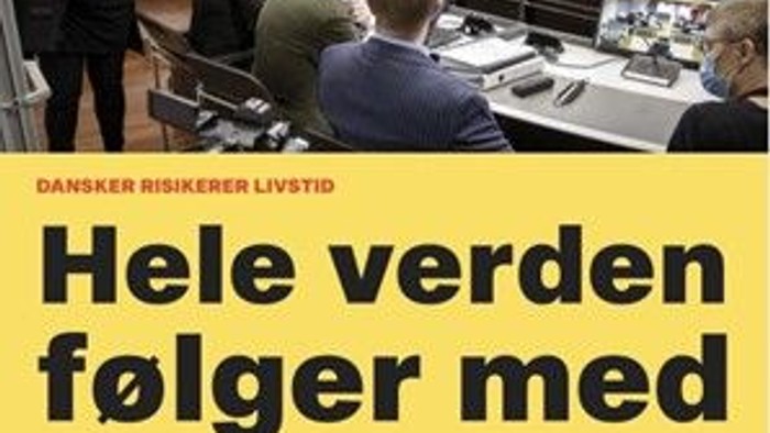 En gruppe af journalister i en redaktion med laptopter og skrivebordsudstyr, med teksten "Hele verden følger med BREAKING"