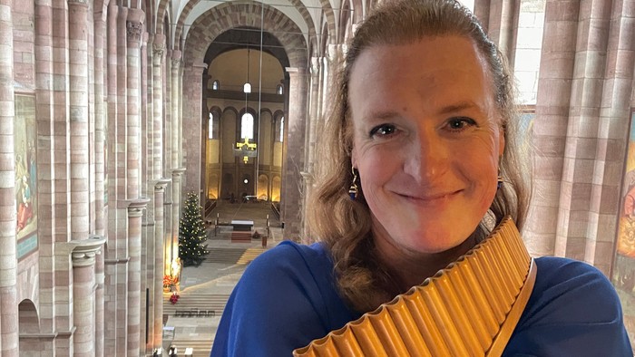 Frau in blauem Mantel mit gelber Schärpe in großer Kirche