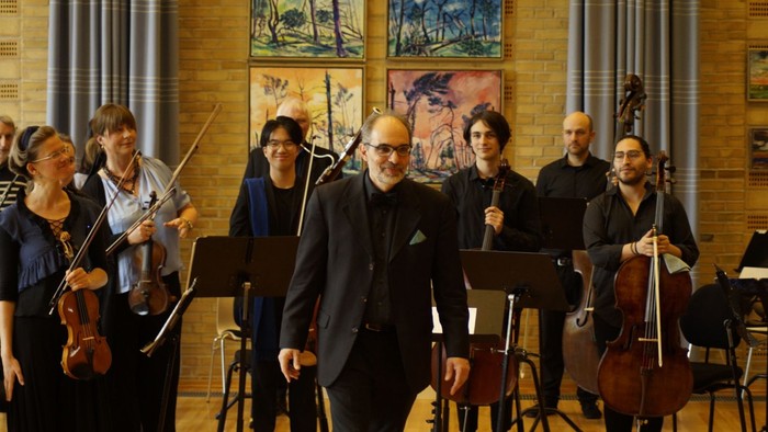 Eine Gruppe von Musikern proben in einem Raum mit Gemälden an den Wänden.