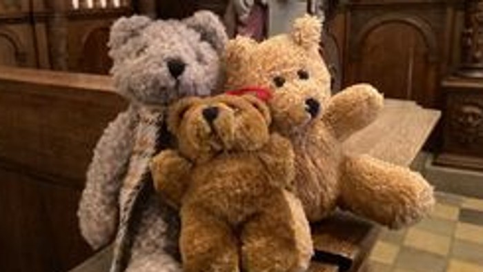 Tre teddybjørne sidder sammen på en bænk.