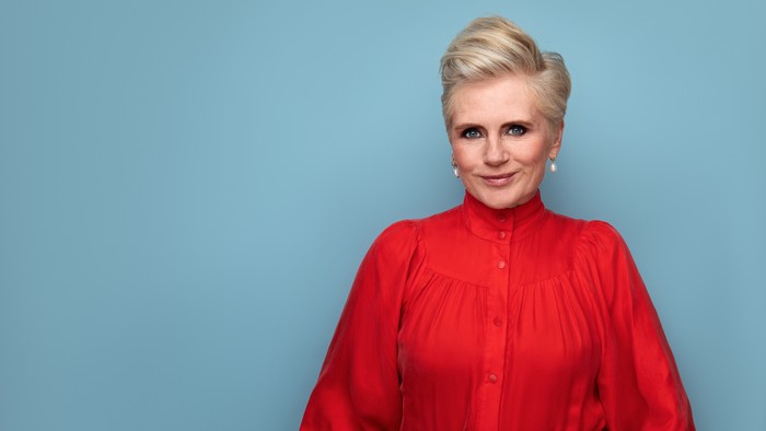 En kvinde med kort, blond hår og en rød bluse.