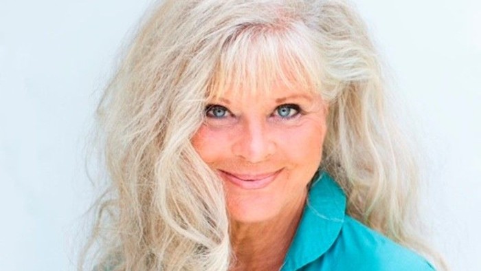 En kvinde med lang, blond hår og et grønt skjorte.