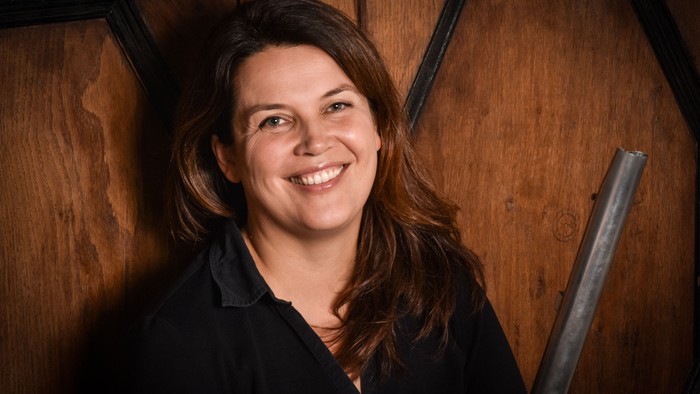 En kvinde med langt brunt hår smiler til kameraet.