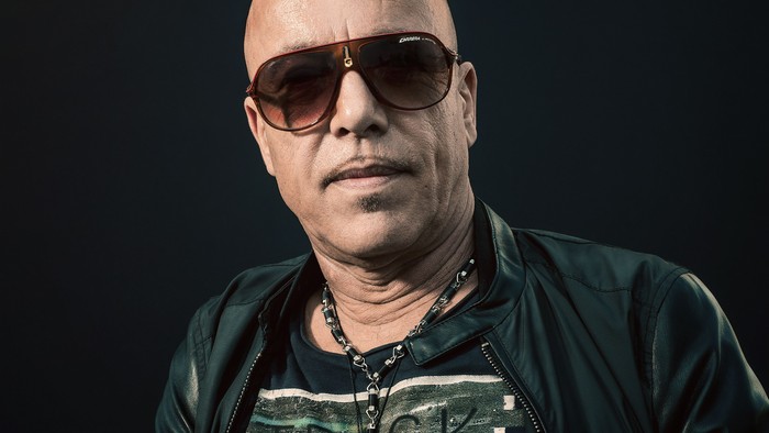 Ein Mann mit Sonnenbrille und Lederjacke posiert selbstbewusst.