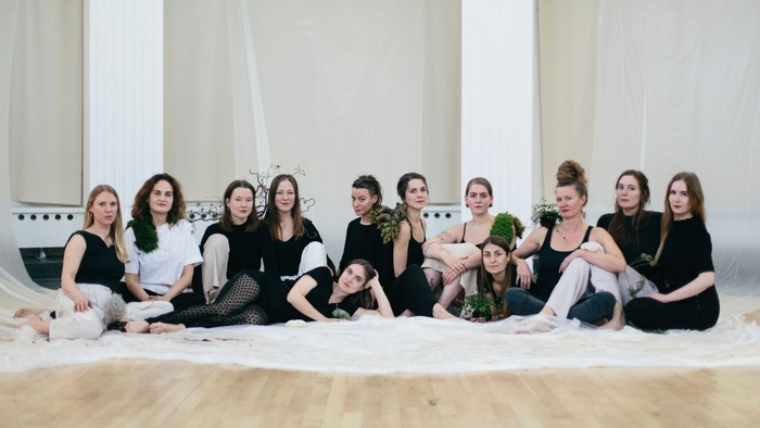 En gruppe kvinder sidder sammen på en hvid klæde på gulv.