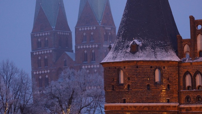 Gothischer Kirchturm bei Dämmerung, beleuchtet und mit Schnee bedeckt
