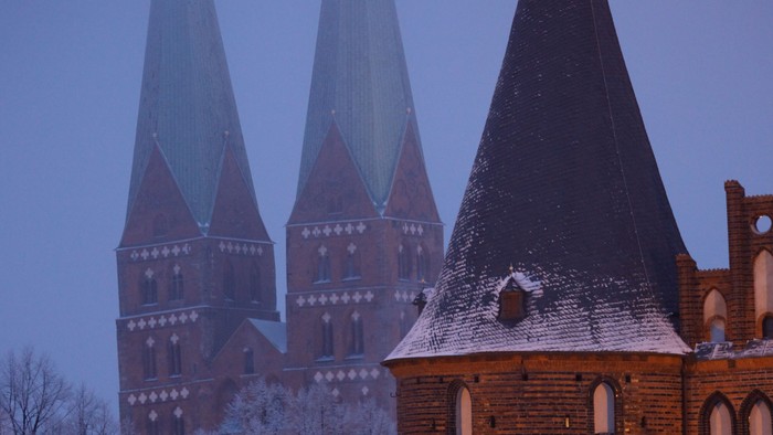Gothischer Kirchturm bei Dämmerung, beleuchtet und mit Schnee bedeckt