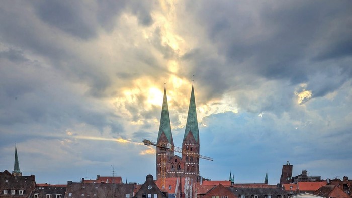 Zwei Kirchtürme spiegeln sich im Wasser, umgeben von Gebäuden und Autos