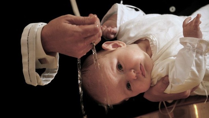 Et barn bliver rynket i en dåbskælde.