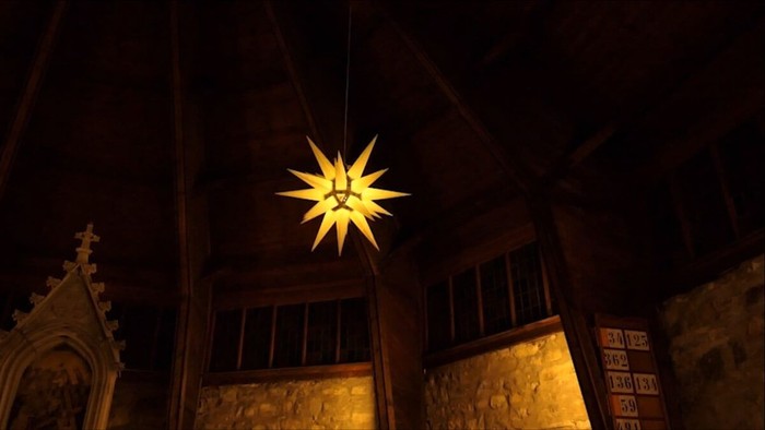 Ein leuchtender Stern hängt in einer dunklen Kirche.