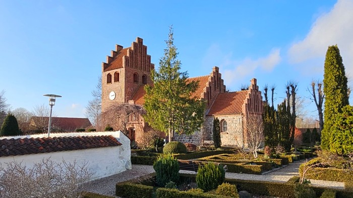 En smuk have med formede hegn og en stor kirke i baggrunden