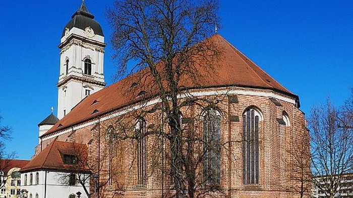 Kirchengebäude mit hohem Turm und rotem Dach unter blauem Himmel