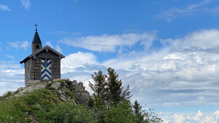 Kleine Kapelle auf felsigem Gipfel unter blauem Himmel