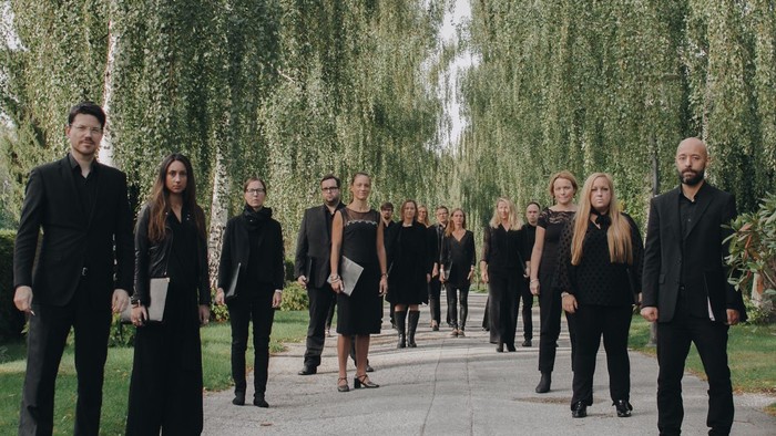 Eine Gruppe von Menschen in Schwarz geht einen Weg entlang, umgeben von Bäumen.