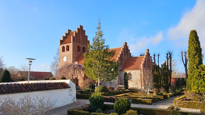 En smuk have med formede hegn og en stor kirke i baggrunden