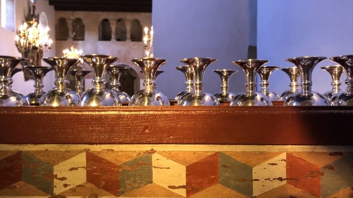 En rekke lyse lysestake på en bænk med farvede malet dekoration.