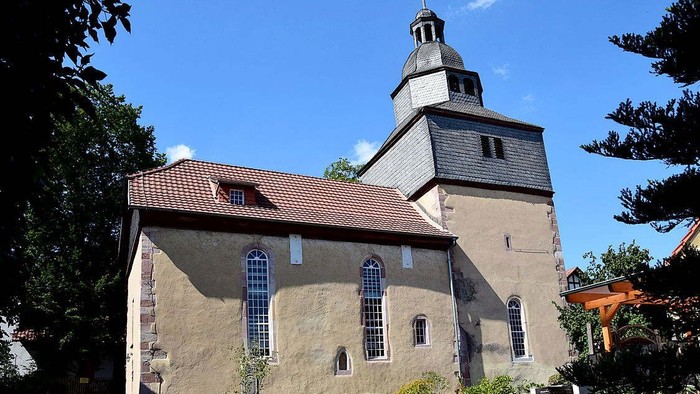 Kirchengebäude mit hohem Turm und rotem Dach unter blauem Himmel