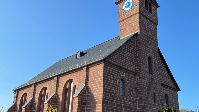 Kirche mit hohem Uhrturm und Rundbogenfenstern.