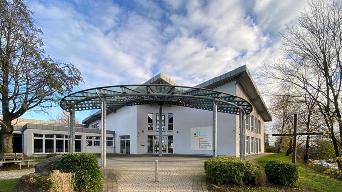 Modernes Gebäude mit Glasvordach und gepflegtem Außenbereich