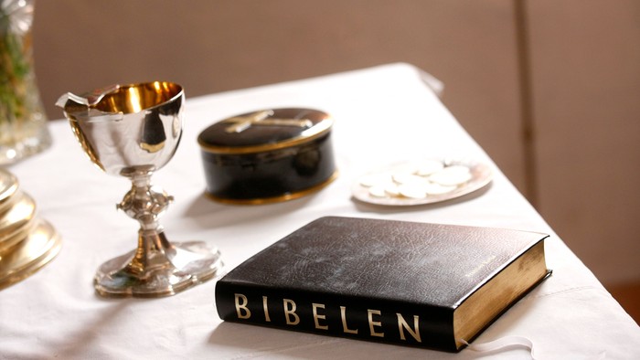 En skål, en boks og en bibel på bord med hvid duk