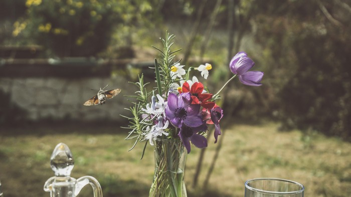 Blumenstrauß in Glasvase auf Tisch im Garten