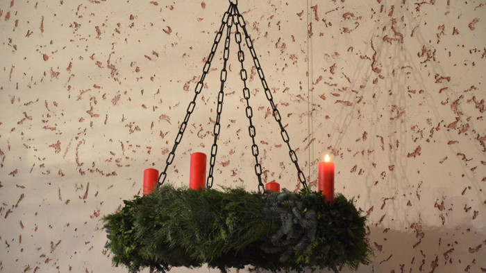 Ein Weihnachtsdekoration mit Tannengrün und roten Kerzen hängt an der Decke