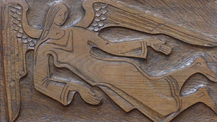 Das Bild zeigt eine detaillierte Holzschnitzerei eines geflügelten Engels.