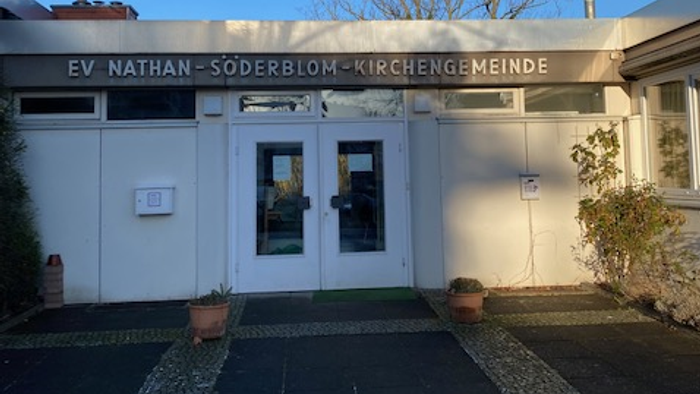 Das Gebäude der EV Nathan-Söderblom-Kirchengemeinde mit Eingangstür und Topfblumen.