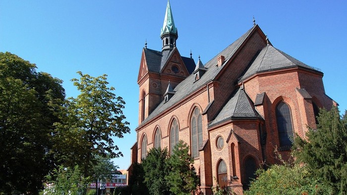 Die Kirche hat einen hohen Turm und ein rotes Dach.