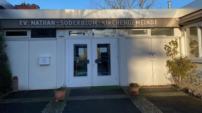 Das Gebäude der EV Nathan-Söderblom-Kirchengemeinde mit Eingangstür und Topfblumen.