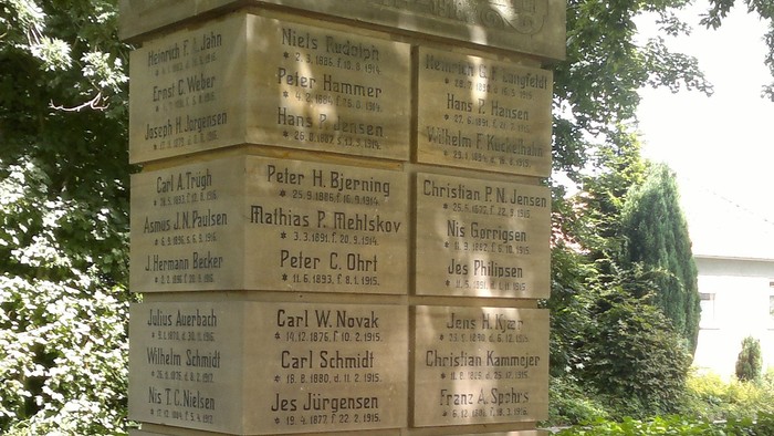 En mindesten med inskriptioner og blomster ved foderen