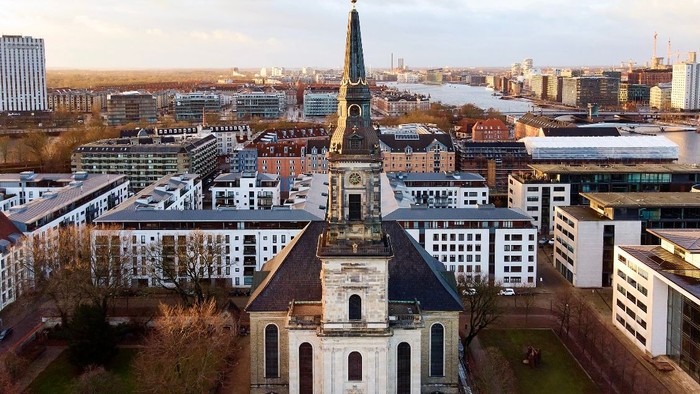 Byen med kirke med højt tårn og moderne bygninger.