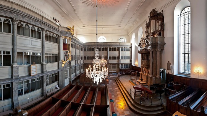 Stor og luksuriøs bibliotekshal med høje boksregale, fine kandelier og store vinduer.