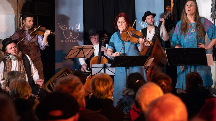 Eine Gruppe von Musikern spielt auf einer Bühne vor einem Publikum