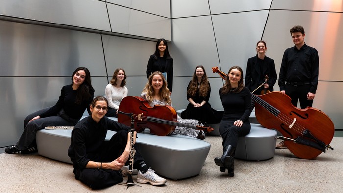 En gruppe musikere poser med deres celler i et moderne indgangsrum